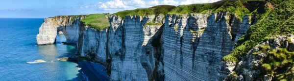 Explore the stunning cliffs of Étretat in Normandy with sweeping views over the sea and sky.
